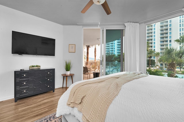 bedroom with wood finished floors, a ceiling fan, baseboards, access to outside, and floor to ceiling windows