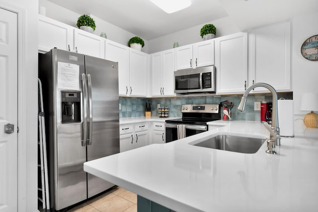 kitchen featuring appliances with stainless steel finishes, light countertops, a sink, and backsplash