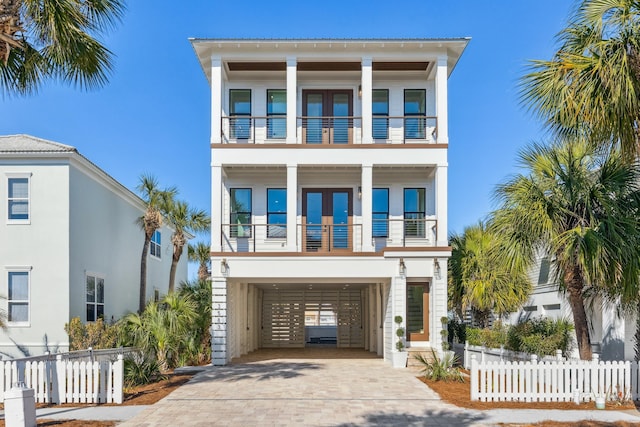 beach home with a carport, decorative driveway, fence, and a balcony