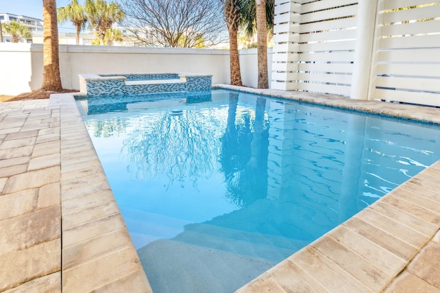 view of pool featuring fence, a fenced in pool, and an in ground hot tub