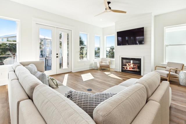 living room with recessed lighting, a fireplace, wood finished floors, and french doors