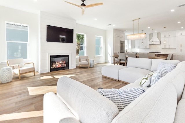 living room with light wood-style floors, recessed lighting, a large fireplace, and visible vents