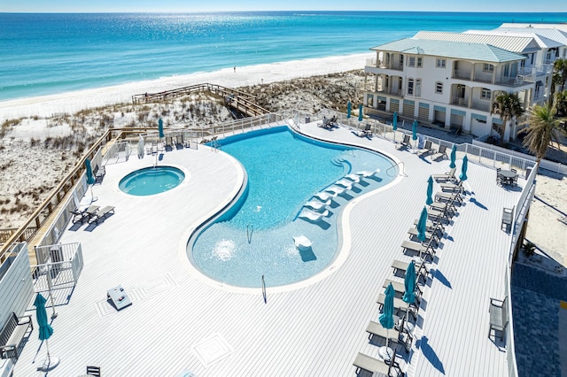 pool featuring fence, a beach view, a community hot tub, and a patio