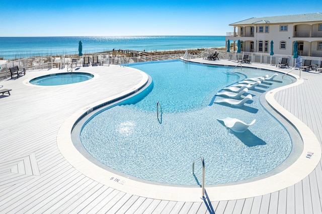 pool featuring a water view, a patio, a hot tub, and fence