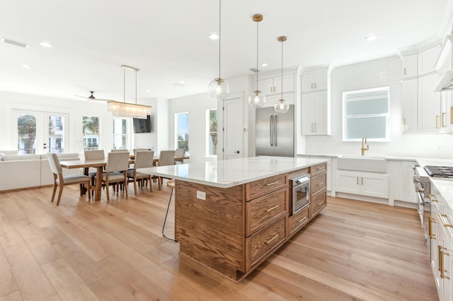 kitchen with a sink, visible vents, appliances with stainless steel finishes, a center island, and brown cabinetry