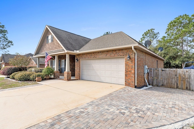 view of front of property with brick siding, roof with shingles, concrete driveway, fence, and a garage