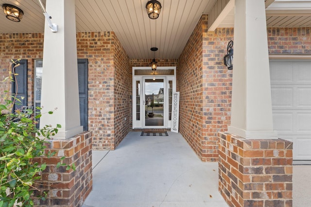 property entrance with covered porch, brick siding, and a garage