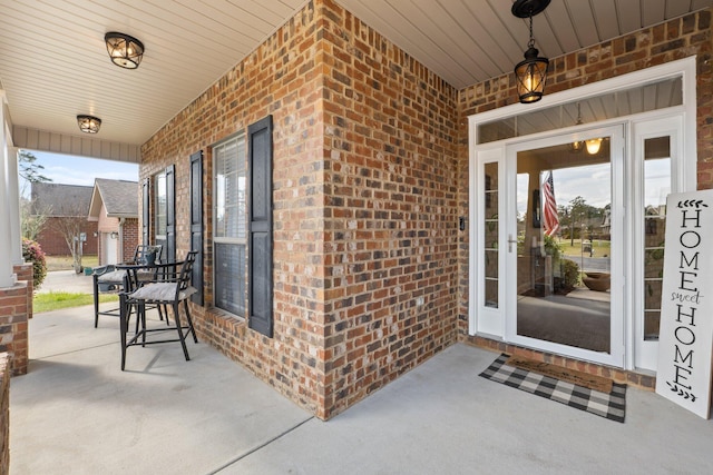 view of exterior entry featuring a porch and brick siding