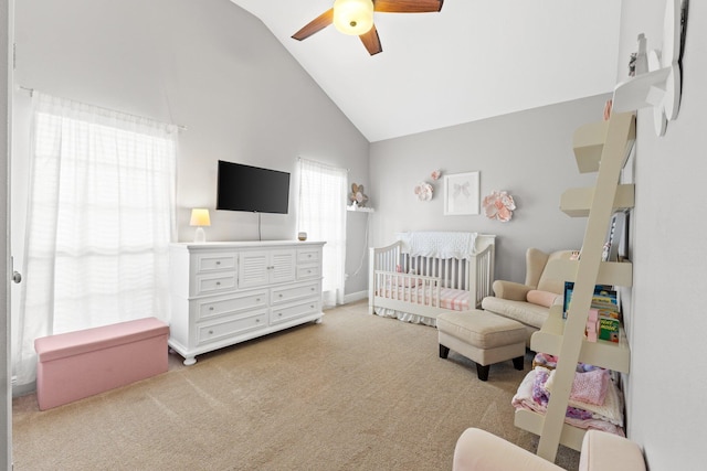 bedroom with carpet floors, a nursery area, high vaulted ceiling, and a ceiling fan