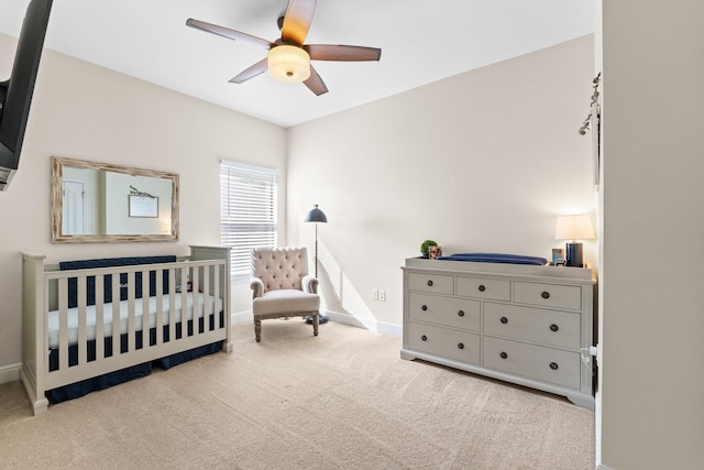 carpeted bedroom with a nursery area, baseboards, and a ceiling fan