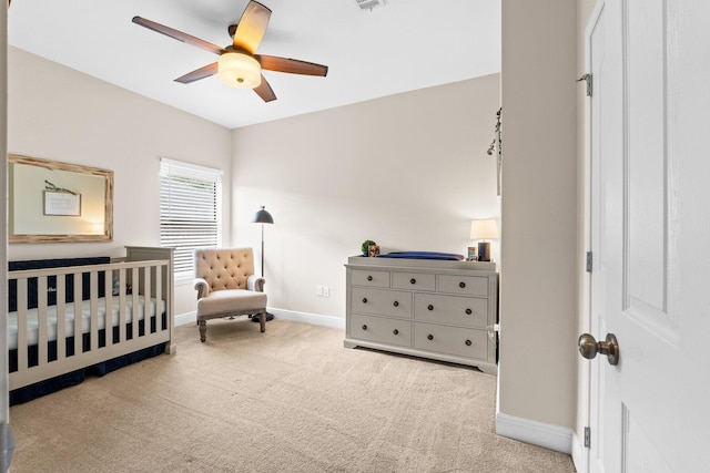 bedroom featuring a crib, visible vents, baseboards, a ceiling fan, and carpet flooring