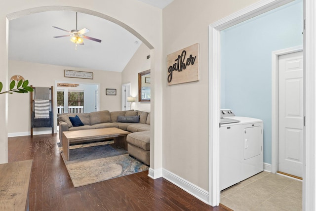 living room featuring baseboards, ceiling fan, wood finished floors, washing machine and clothes dryer, and vaulted ceiling