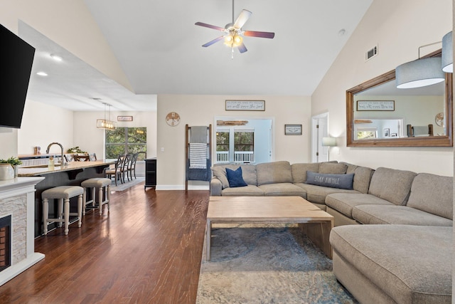 living area featuring visible vents, ceiling fan, dark wood-type flooring, a fireplace, and high vaulted ceiling