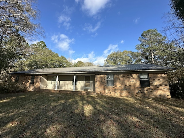 back of house featuring brick siding and a lawn