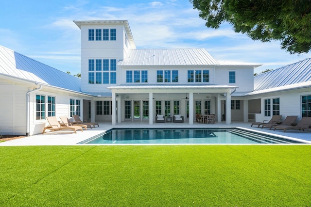 back of house featuring metal roof, a patio, a yard, and an outdoor pool