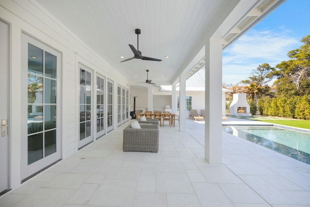 view of patio with a ceiling fan, outdoor dining area, and a fireplace