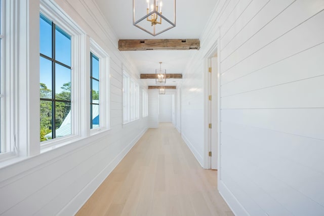 hallway featuring light wood-style floors, beamed ceiling, and baseboards