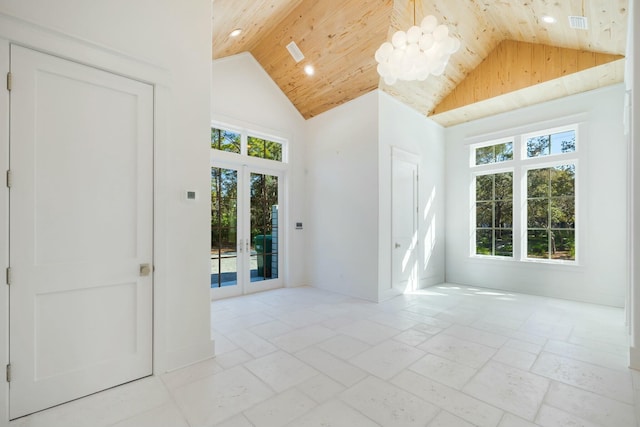 empty room with high vaulted ceiling, stone tile floors, wooden ceiling, and a healthy amount of sunlight