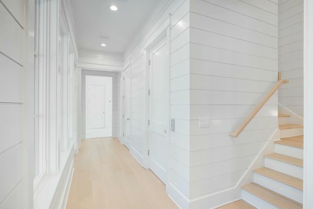 hallway with wooden walls, stairway, light wood-type flooring, and recessed lighting