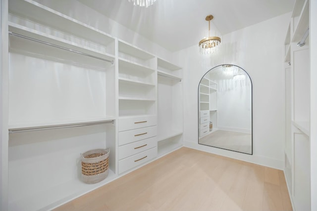 walk in closet featuring light wood-style floors and a notable chandelier