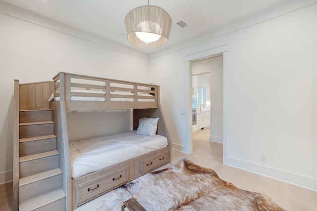 bedroom featuring visible vents, baseboards, wood finished floors, and ornamental molding