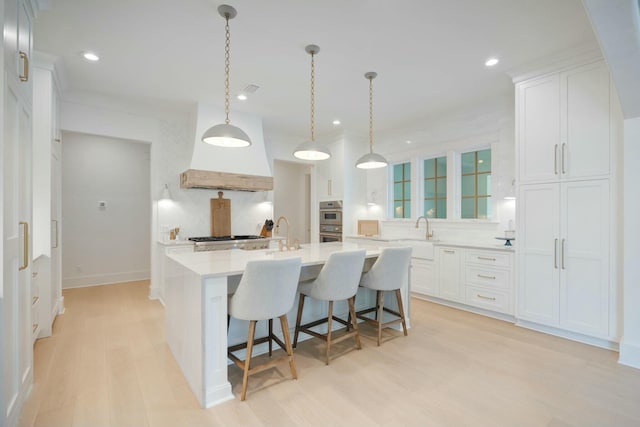 kitchen featuring appliances with stainless steel finishes, light countertops, light wood-style floors, and white cabinetry