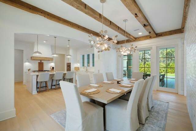 dining area with light wood finished floors, a chandelier, and beam ceiling