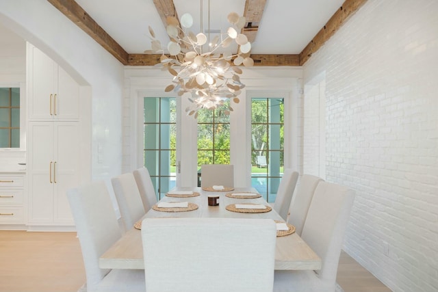 dining space featuring brick wall, light wood finished floors, beam ceiling, and a notable chandelier