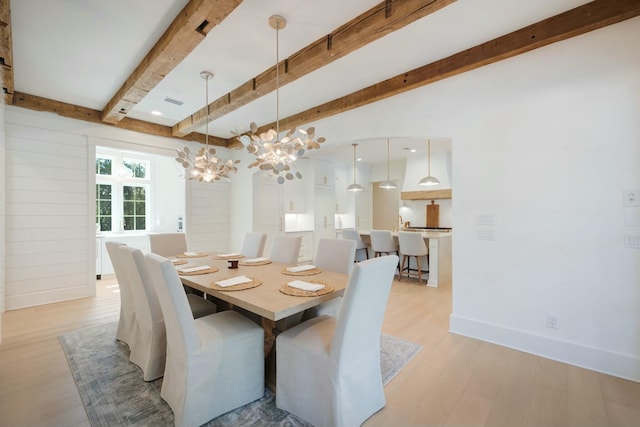 dining room with a chandelier, beam ceiling, light wood-style flooring, and baseboards