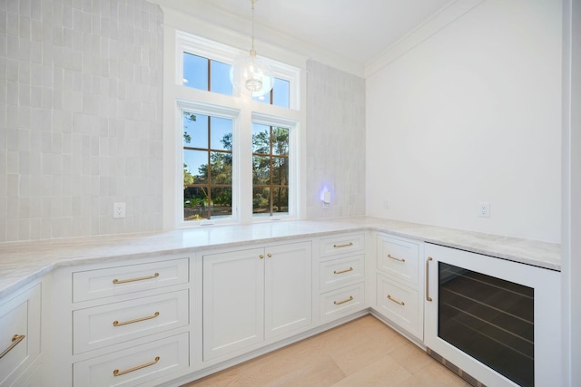 kitchen featuring beverage cooler, white cabinets, decorative backsplash, decorative light fixtures, and light stone countertops