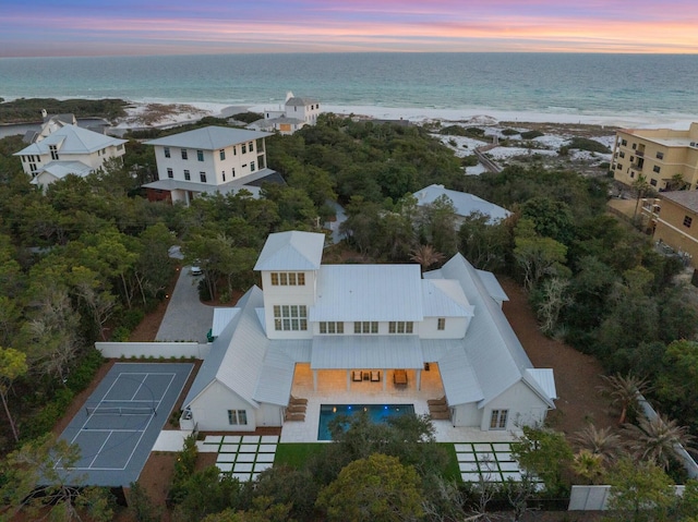 aerial view at dusk with a water view and a beach view