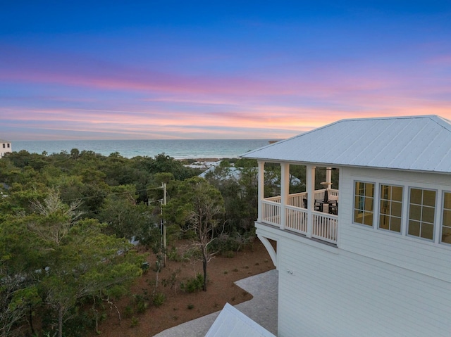 property exterior at dusk with metal roof and a water view