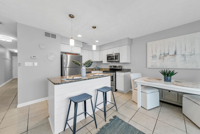 kitchen featuring appliances with stainless steel finishes, light tile patterned flooring, a kitchen bar, and visible vents