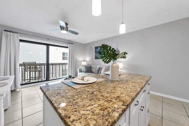 kitchen with light stone countertops, white cabinets, a kitchen island, and light tile patterned floors