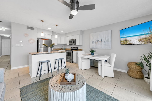 kitchen with light tile patterned floors, stainless steel appliances, visible vents, and white cabinetry