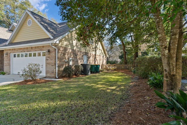 view of side of home featuring roof with shingles, brick siding, a lawn, an attached garage, and driveway