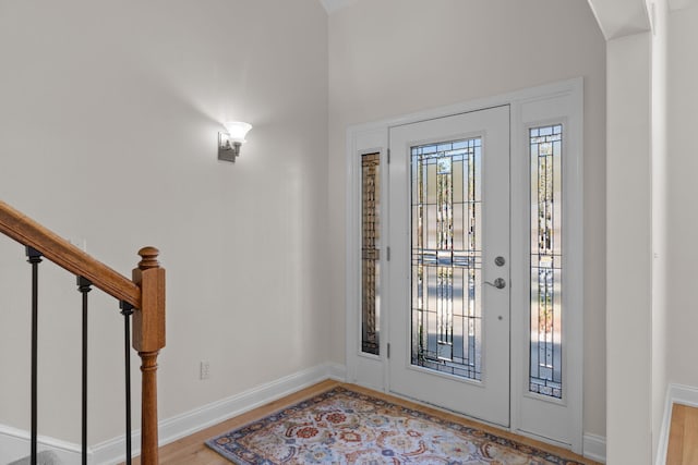 entrance foyer with light wood-type flooring, stairway, and baseboards