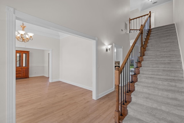 stairway featuring baseboards, wood finished floors, and a notable chandelier