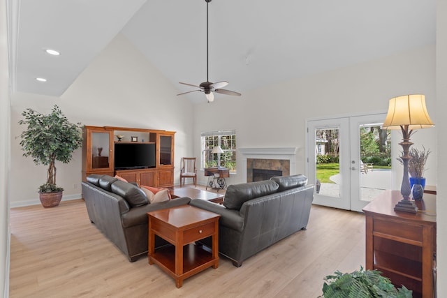 living room with french doors, a fireplace, recessed lighting, light wood-style flooring, and high vaulted ceiling