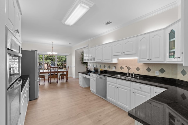 kitchen featuring tasteful backsplash, white cabinets, appliances with stainless steel finishes, ornamental molding, and a sink