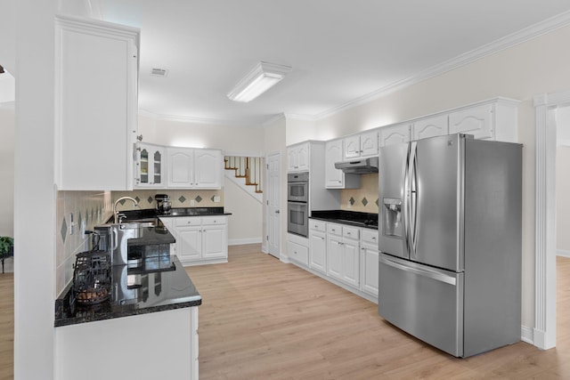 kitchen with light wood-type flooring, under cabinet range hood, stainless steel appliances, and a sink