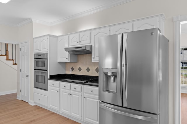 kitchen featuring under cabinet range hood, appliances with stainless steel finishes, backsplash, dark countertops, and crown molding