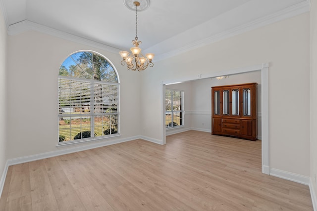 unfurnished dining area with baseboards, light wood finished floors, ornamental molding, and an inviting chandelier