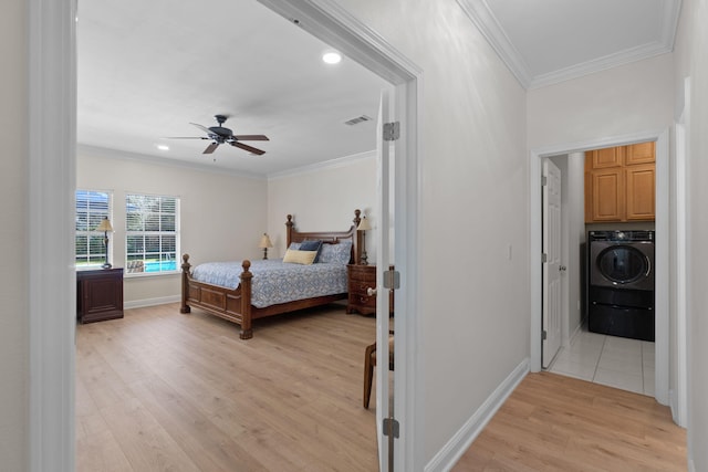 bedroom with visible vents, baseboards, ornamental molding, light wood finished floors, and washer / dryer