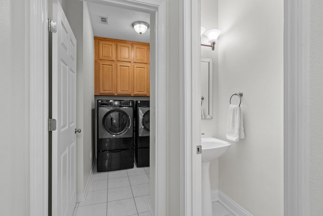 bathroom featuring tile patterned flooring, washing machine and dryer, visible vents, and baseboards