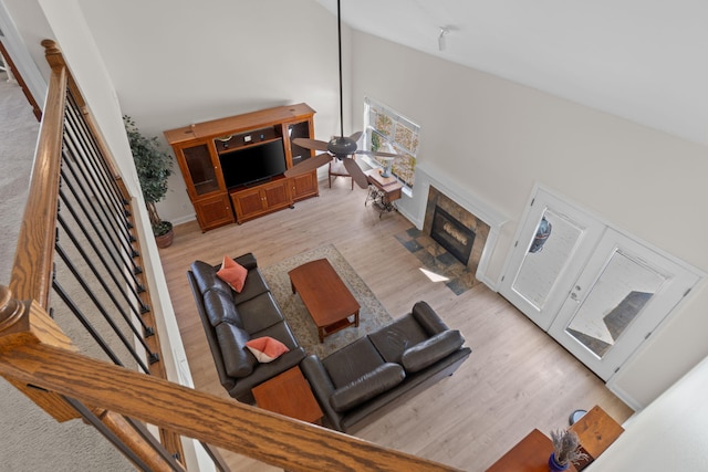 living room featuring a fireplace, a towering ceiling, baseboards, light wood-style floors, and stairway