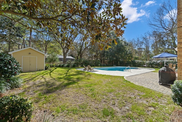 view of yard featuring an outbuilding, a patio, a storage shed, a fenced backyard, and an outdoor pool