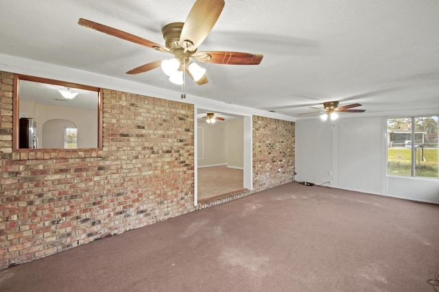 carpeted spare room featuring brick wall