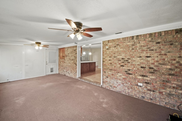 empty room with light colored carpet, visible vents, a ceiling fan, a textured ceiling, and brick wall