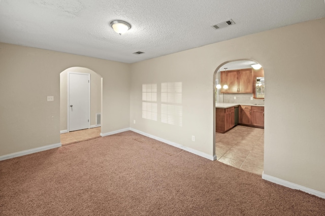 spare room with arched walkways, baseboards, visible vents, and light colored carpet